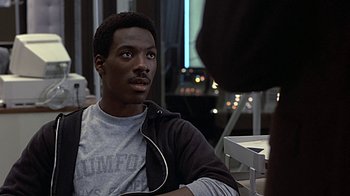 Movie still from “Beverly Hills Cop” (1984), directed by Martin Brest – A man sitting in front of another man in front of a computer screen; Close Up shot, Over the shoulder angle