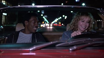 Movie still from “Beverly Hills Cop” (1984), directed by Martin Brest – A man and a woman sitting in the back of a car; Medium shot, Over the shoulder angle