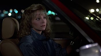 Movie still from “Beverly Hills Cop” (1984), directed by Martin Brest – A woman sitting in the drivers seat of a car at night; Close Up shot, Over the shoulder angle