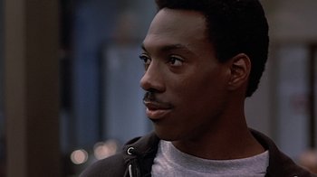 Movie still from “Beverly Hills Cop” (1984), directed by Martin Brest – A person wearing a jacket looking to his left; Close Up shot, Over the shoulder angle