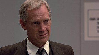 Movie still from “Beverly Hills Cop” (1984), directed by Martin Brest – An older man in a suit and tie looking to his left; Close Up shot, Over the shoulder angle