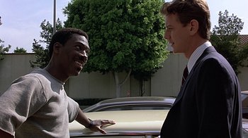 Movie still from “Beverly Hills Cop” (1984), directed by Martin Brest – Two men in business suits talking to each other; Close Up shot, Over the shoulder angle