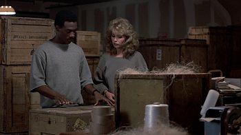 Movie still from “Beverly Hills Cop” (1984), directed by Martin Brest – A man and a woman working in a warehouse; Medium shot, High angle