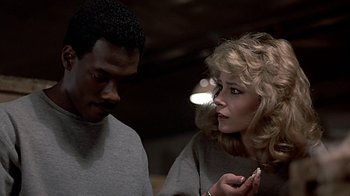 Movie still from “Beverly Hills Cop” (1984), directed by Martin Brest – A man and a woman looking at a cell phone; Close Up shot, Over the shoulder angle