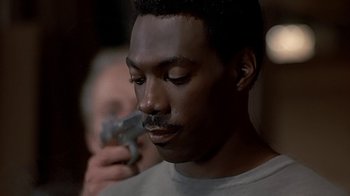 Movie still from “Beverly Hills Cop” (1984), directed by Martin Brest – A person holding a cell phone; Close Up shot, Over the shoulder angle