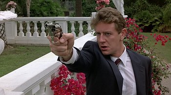 Movie still from “Beverly Hills Cop” (1984), directed by Martin Brest – A man in a suit and tie holding a gun in his hand; Close Up shot, Low angle
