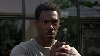 Movie still from “Beverly Hills Cop” (1984), directed by Martin Brest – A man holding a gun in his hand; Close Up shot, High angle