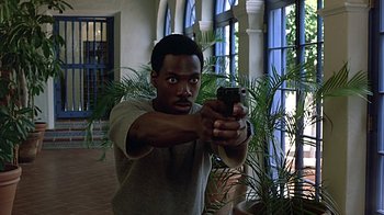 Movie still from “Beverly Hills Cop” (1984), directed by Martin Brest – A man holding a cell phone in his hand; Medium shot, Low angle