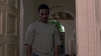 Movie still from “Beverly Hills Cop” (1984), directed by Martin Brest – A man standing in front of an archway in a room; Medium shot, Low angle