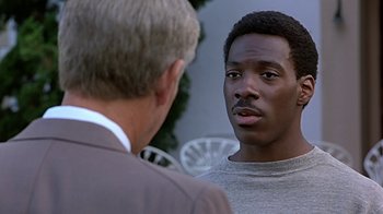 Movie still from “Beverly Hills Cop” (1984), directed by Martin Brest – A man talking to another man in front of a building; Close Up shot, Over the shoulder angle