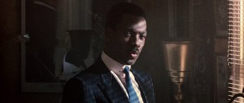 Movie still from “Beverly Hills Cop II” (1987), directed by Tony Scott – A man wearing a suit and tie in a room; Close Up shot, Low angle