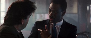 Movie still from “Beverly Hills Cop II” (1987), directed by Tony Scott – A man in a suit and tie pointing at another man; Close Up shot, Over the shoulder angle