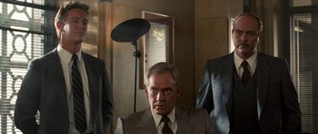 Movie still from “Beverly Hills Cop II” (1987), directed by Tony Scott – A man wearing a suit and tie in a room; Medium shot, Low angle