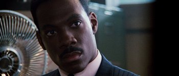 Movie still from “Beverly Hills Cop II” (1987), directed by Tony Scott – A person wearing a suit and tie; Close Up shot, Over the shoulder angle