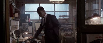 Movie still from “Beverly Hills Cop II” (1987), directed by Tony Scott – A man wearing a suit and tie standing in a room; Medium shot, Low angle