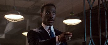 Movie still from “Beverly Hills Cop II” (1987), directed by Tony Scott – A man in a suit and tie throwing a frisbee; Close Up shot, Low angle