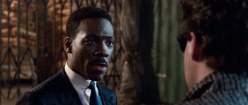 Movie still from “Beverly Hills Cop II” (1987), directed by Tony Scott – A person wearing a suit and tie; Close Up shot, Over the shoulder angle