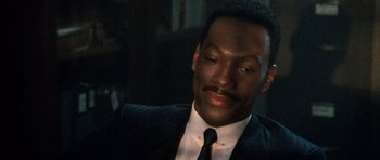 Movie still from “Beverly Hills Cop II” (1987), directed by Tony Scott – A man in a black suit and a white shirt; Close Up shot, Over the shoulder angle
