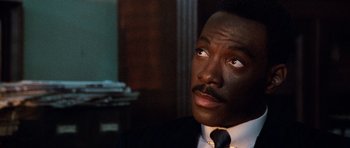 Movie still from “Beverly Hills Cop II” (1987), directed by Tony Scott – A person wearing a suit and a tie; Close Up shot, Low angle