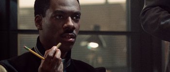 Movie still from “Beverly Hills Cop II” (1987), directed by Tony Scott – A person holding a cigarette in his mouth; Close Up shot, Over the shoulder angle