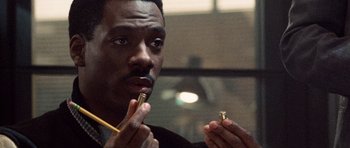 Movie still from “Beverly Hills Cop II” (1987), directed by Tony Scott – A man holding a small object in front of his face; Close Up shot, High angle
