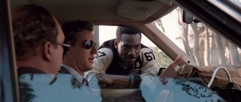 Movie still from “Beverly Hills Cop II” (1987), directed by Tony Scott – Two men are sitting in the back of a car; Medium shot, Over the shoulder angle