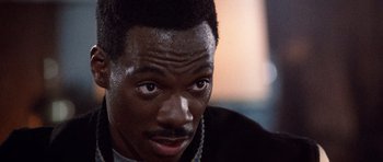 Movie still from “Beverly Hills Cop II” (1987), directed by Tony Scott – A person wearing a necklace; Close Up shot, High angle