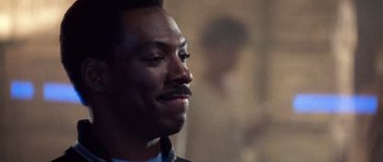 Movie still from “Beverly Hills Cop II” (1987), directed by Tony Scott – A person wearing a suit and tie; Close Up shot, Over the shoulder angle