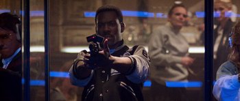 Movie still from “Beverly Hills Cop II” (1987), directed by Tony Scott – A man holding a gun while standing in front of a wall; Medium shot, Low angle