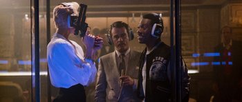 Movie still from “Beverly Hills Cop II” (1987), directed by Tony Scott – Two men and a woman wearing ear muffs and headphones; Medium shot, Over the shoulder angle