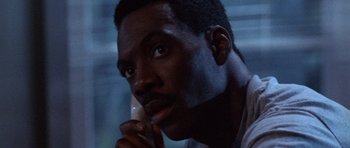 Movie still from “Beverly Hills Cop II” (1987), directed by Tony Scott – A person talking on a cell phone; Close Up shot, Low angle
