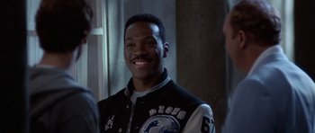 Movie still from “Beverly Hills Cop II” (1987), directed by Tony Scott – A man smiling for the camera wearing a black and white jacket; Close Up shot, Over the shoulder angle