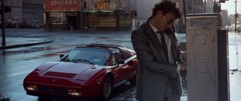 Movie still from “Beverly Hills Cop II” (1987), directed by Tony Scott – A man standing next to a red sports car on the street; Wide shot, Low angle