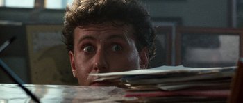 Movie still from “Beverly Hills Cop II” (1987), directed by Tony Scott – A person looking over a pile of papers; Close Up shot, Low angle