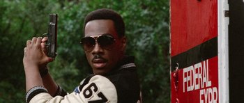 Movie still from “Beverly Hills Cop II” (1987), directed by Tony Scott – A man in a black and white jacket wearing sunglasses; Close Up shot, Low angle