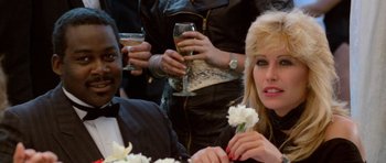 Movie still from “Beverly Hills Cop II” (1987), directed by Tony Scott – A group of people sitting at a table holding flowers; Close Up shot, Low angle
