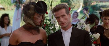 Movie still from “Beverly Hills Cop II” (1987), directed by Tony Scott – A man and a woman standing next to each other in front of flowers; Close Up shot, Over the shoulder angle