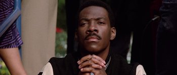Movie still from “Beverly Hills Cop II” (1987), directed by Tony Scott – A person with their hands clasped together; Close Up shot, Low angle