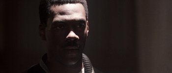 Movie still from “Beverly Hills Cop II” (1987), directed by Tony Scott – A person wearing a necklace; Close Up shot, Over the shoulder angle