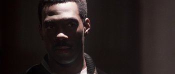 Movie still from “Beverly Hills Cop II” (1987), directed by Tony Scott – A person wearing a necklace; Close Up shot, Over the shoulder angle