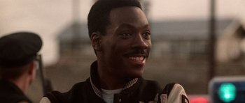 Movie still from “Beverly Hills Cop II” (1987), directed by Tony Scott – A person with a smile on their face; Close Up shot, Low angle