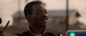 Movie still from “Beverly Hills Cop II” (1987), directed by Tony Scott – A person with a beard and mustache; Close Up shot, Over the shoulder angle