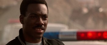 Movie still from “Beverly Hills Cop II” (1987), directed by Tony Scott – A person wearing a necklace; Close Up shot, Over the shoulder angle