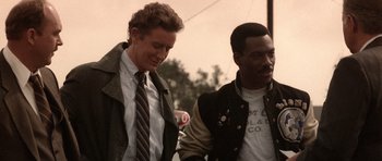 Movie still from “Beverly Hills Cop II” (1987), directed by Tony Scott – Two young men walking down a street holding hands; Medium shot, Over the shoulder angle