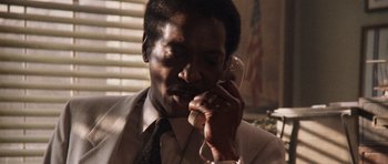 Movie still from “Beverly Hills Cop II” (1987), directed by Tony Scott – A man in a white suit talking on a phone; Close Up shot, Low angle