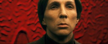 A man's face in front of a red background