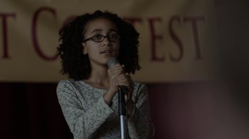 Movie still from “Beyond the Lights” (2014), directed by Gina Prince-Bythewood – A young girl holding a microphone in front of a crowd; Close Up shot, Over the shoulder angle