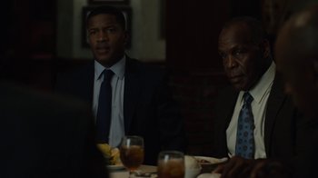 Movie still from “Beyond the Lights” (2014), directed by Gina Prince-Bythewood – A couple of men sitting at a table with drinks; Medium shot, Over the shoulder angle