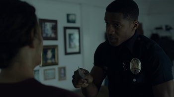 Movie still from “Beyond the Lights” (2014), directed by Gina Prince-Bythewood – A police officer is holding something in his hand; Medium shot, Over the shoulder angle