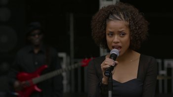 Movie still from “Beyond the Lights” (2014), directed by Gina Prince-Bythewood – A woman is holding a microphone up to her mouth; Medium shot, Over the shoulder angle